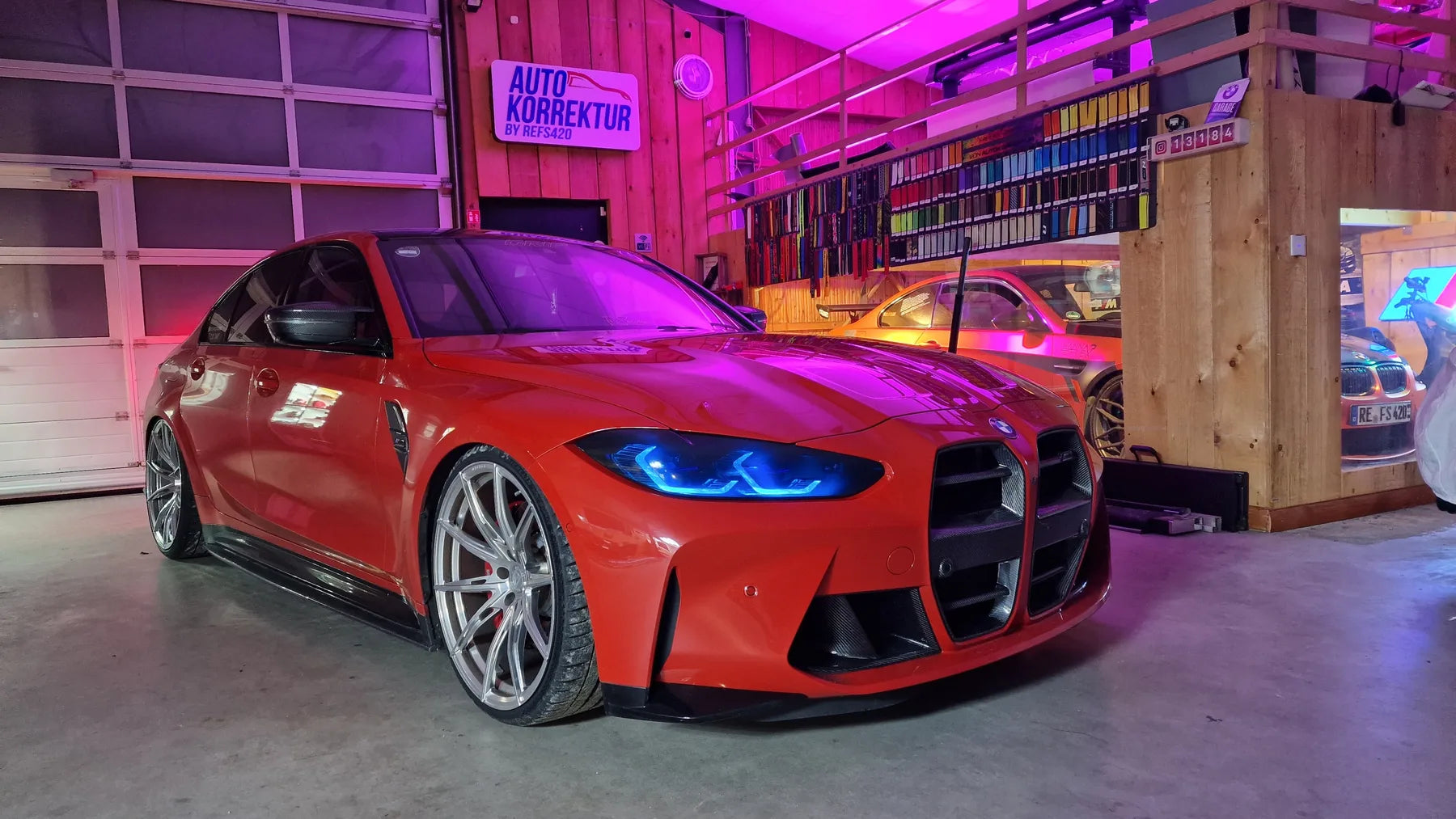 Scheinwerfercover passend für BMW M3 G80, rotes Fahrzeug mit blau leuchtenden Scheinwerfern in der Autokorrektur-Werkstatt